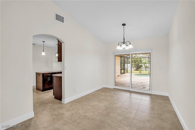 spare room with lofted ceiling, light tile patterned floors, and a chandelier