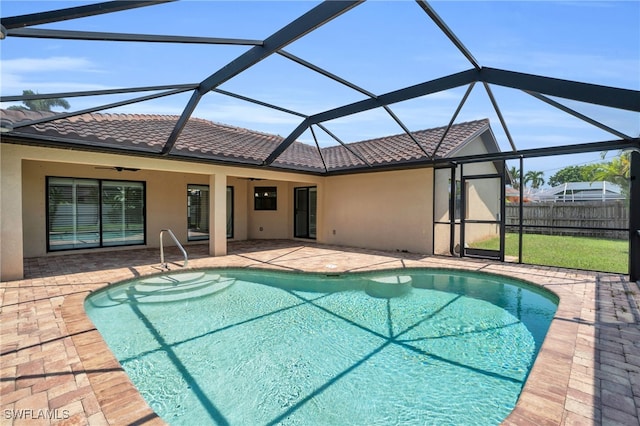 view of swimming pool featuring a patio, ceiling fan, and glass enclosure