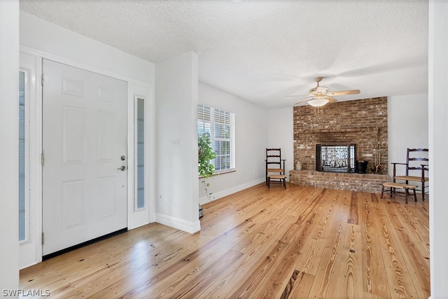 foyer featuring a textured ceiling, a brick fireplace, and light hardwood / wood-style floors