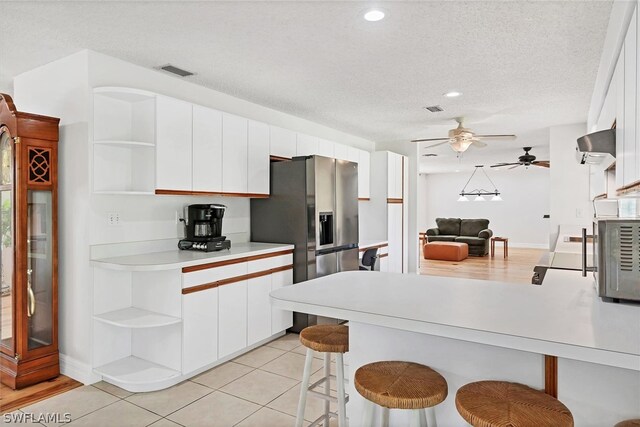 kitchen featuring a breakfast bar, white cabinetry, kitchen peninsula, and ceiling fan