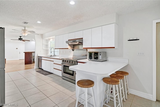 kitchen featuring appliances with stainless steel finishes, light hardwood / wood-style floors, a textured ceiling, white cabinetry, and ceiling fan