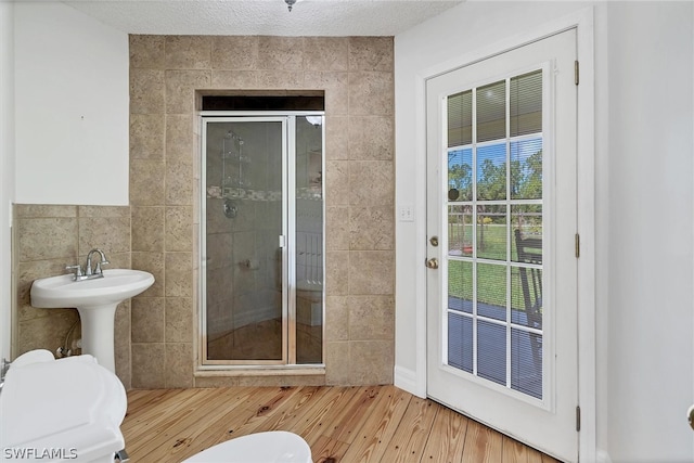 bathroom featuring a shower with door, tile walls, and hardwood / wood-style flooring