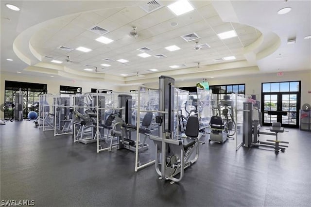 gym featuring french doors, a tray ceiling, and a drop ceiling