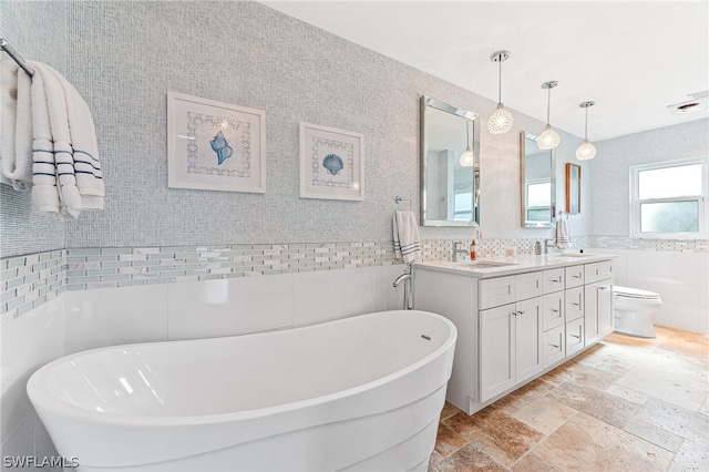 bathroom featuring vanity, toilet, a bath, and tile walls