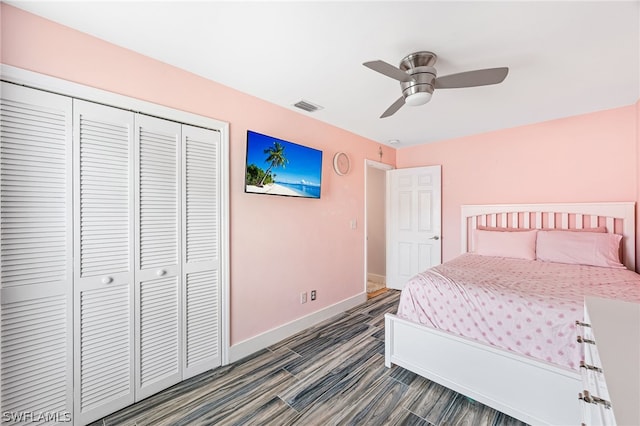 bedroom with dark wood-type flooring, ceiling fan, and a closet