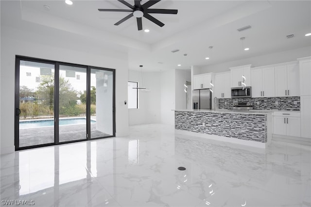 kitchen with decorative backsplash, a tray ceiling, decorative light fixtures, white cabinetry, and appliances with stainless steel finishes