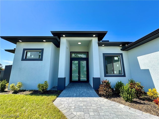 entrance to property with french doors and a lawn