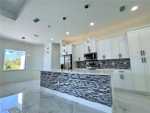 kitchen featuring a kitchen island with sink, decorative light fixtures, white cabinetry, and stainless steel appliances