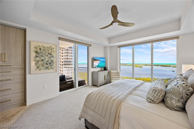 bedroom with ceiling fan, a raised ceiling, light carpet, and access to outside