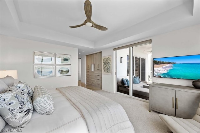 bedroom featuring ceiling fan, access to exterior, a raised ceiling, and light carpet