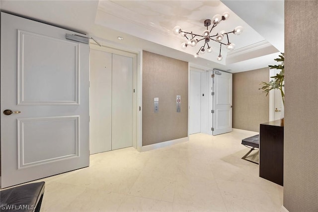 corridor featuring ornamental molding, a tray ceiling, and a notable chandelier