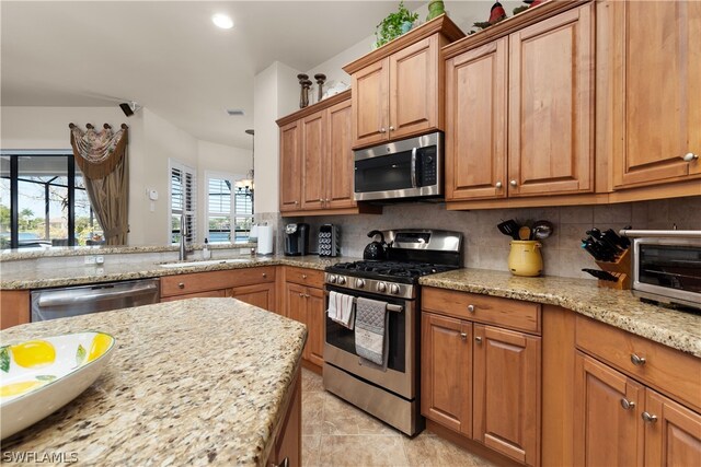 kitchen featuring appliances with stainless steel finishes, light tile patterned floors, backsplash, and light stone countertops