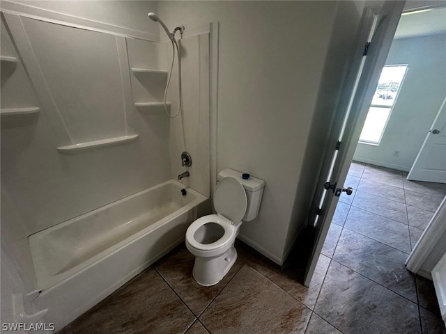 bathroom with tile patterned floors, washtub / shower combination, and toilet