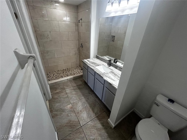 bathroom featuring a tile shower, vanity, and toilet