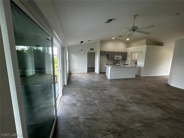 kitchen with sink, vaulted ceiling, a kitchen island with sink, and ceiling fan