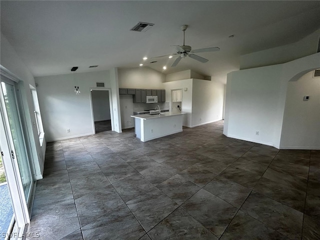 kitchen with ceiling fan, sink, decorative light fixtures, a center island with sink, and lofted ceiling