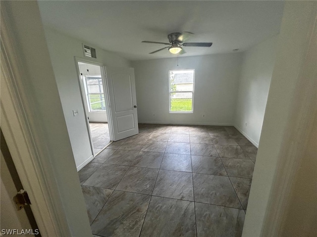 tiled empty room featuring ceiling fan