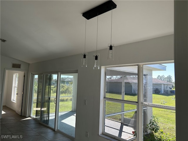 entryway with dark tile patterned flooring, a wealth of natural light, and lofted ceiling