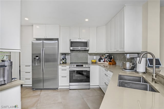 kitchen with stainless steel appliances, sink, white cabinets, and decorative backsplash