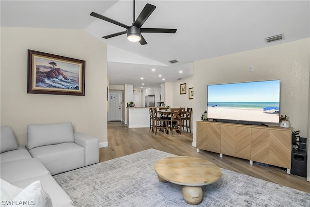 living room with ceiling fan, lofted ceiling, and light hardwood / wood-style floors