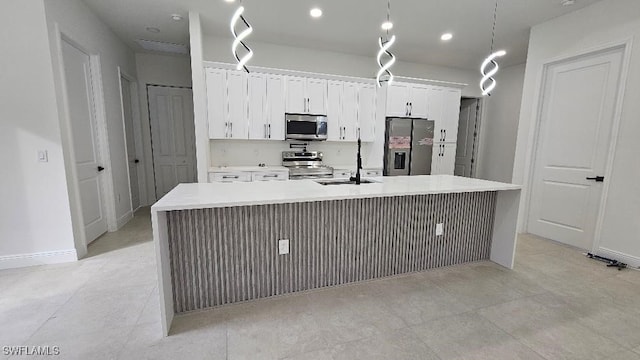 kitchen featuring sink, stainless steel appliances, an island with sink, and white cabinetry