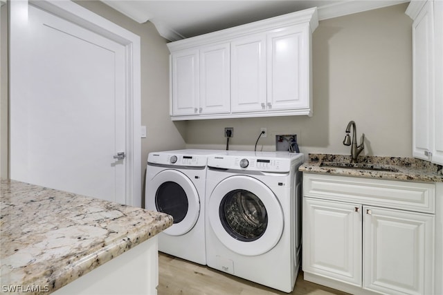 clothes washing area featuring cabinets, light wood-type flooring, ornamental molding, sink, and separate washer and dryer