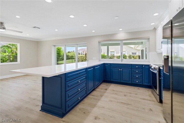 kitchen with kitchen peninsula, appliances with stainless steel finishes, ceiling fan, blue cabinetry, and light hardwood / wood-style floors