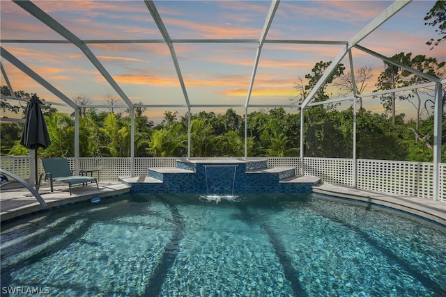 pool at dusk with pool water feature and a lanai