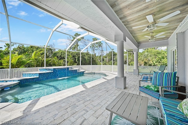 view of swimming pool featuring a lanai, a patio area, ceiling fan, pool water feature, and a hot tub