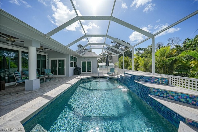 view of pool featuring a patio, glass enclosure, ceiling fan, pool water feature, and a hot tub