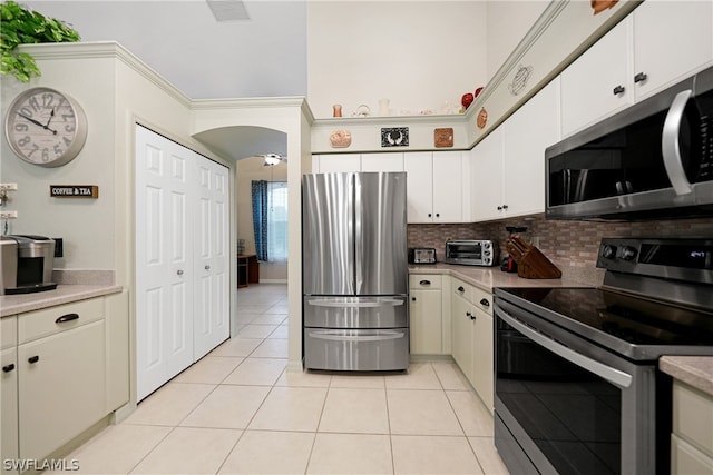 kitchen with crown molding, tasteful backsplash, stainless steel appliances, and light tile patterned floors