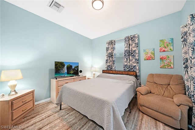 bedroom featuring light wood-style flooring, visible vents, and baseboards