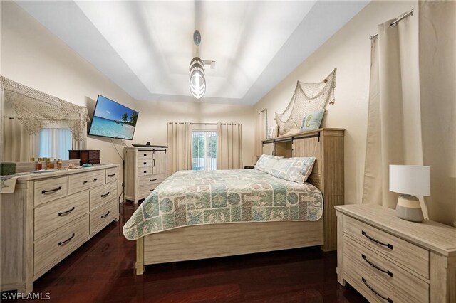 bedroom with dark wood-type flooring and a raised ceiling