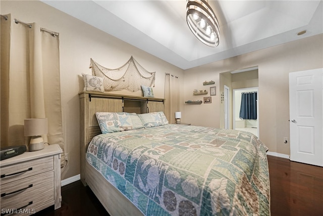 bedroom with dark hardwood / wood-style floors and a tray ceiling