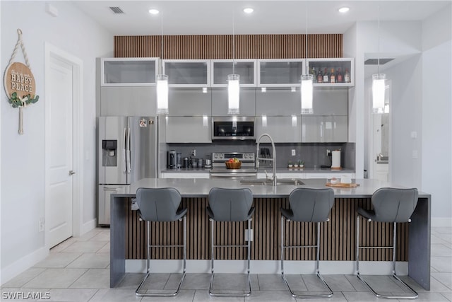 kitchen with light tile patterned flooring, stainless steel appliances, a breakfast bar, and tasteful backsplash