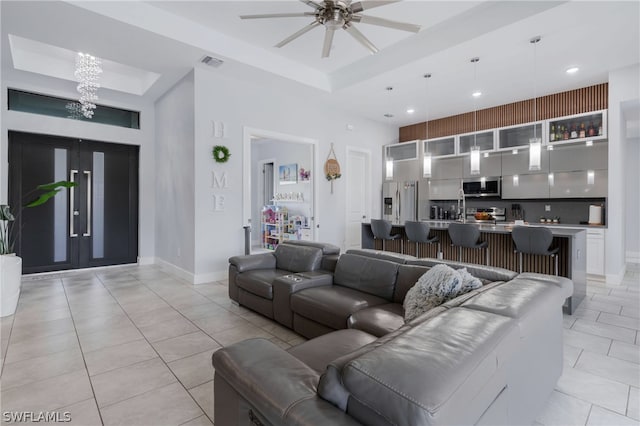 tiled living room featuring a raised ceiling, ceiling fan, and a towering ceiling