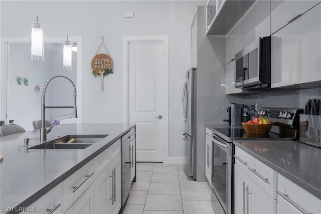 kitchen with stainless steel appliances, pendant lighting, white cabinets, dark stone countertops, and light tile patterned floors