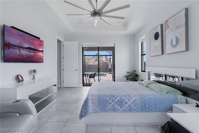 tiled bedroom featuring ceiling fan, access to outside, and a tray ceiling