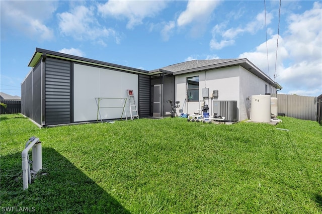 rear view of house featuring central air condition unit, a yard, and an outbuilding