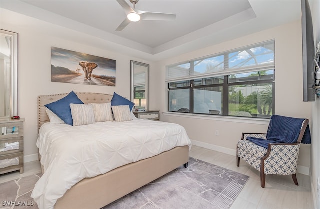 bedroom with ceiling fan and a raised ceiling