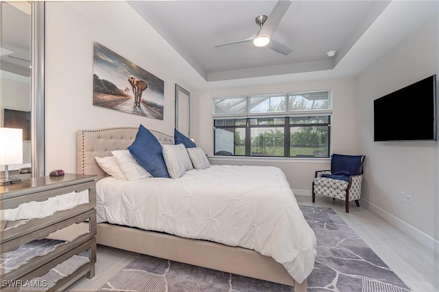 bedroom with ceiling fan and a tray ceiling