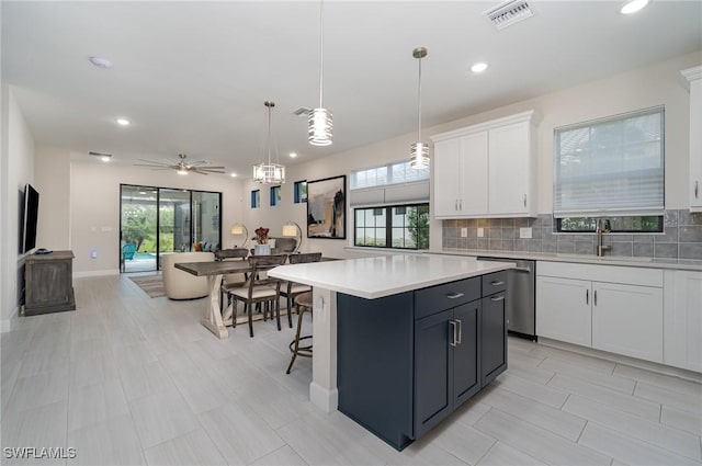 kitchen with a kitchen island, pendant lighting, sink, white cabinets, and stainless steel dishwasher