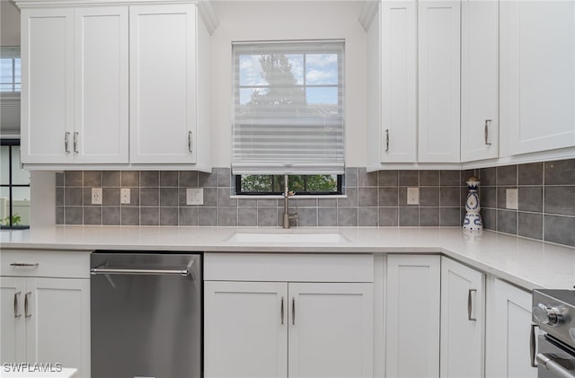 kitchen featuring appliances with stainless steel finishes, sink, decorative backsplash, light stone countertops, and white cabinetry