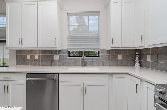 kitchen with sink, white cabinetry, light stone counters, appliances with stainless steel finishes, and backsplash