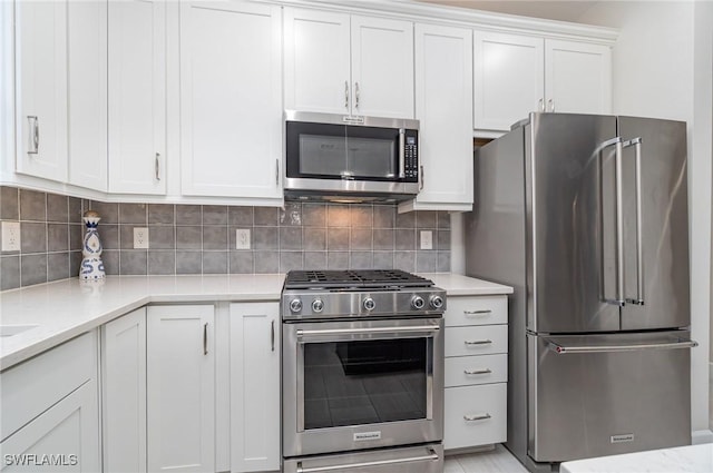 kitchen featuring white cabinetry, appliances with stainless steel finishes, light stone counters, and decorative backsplash