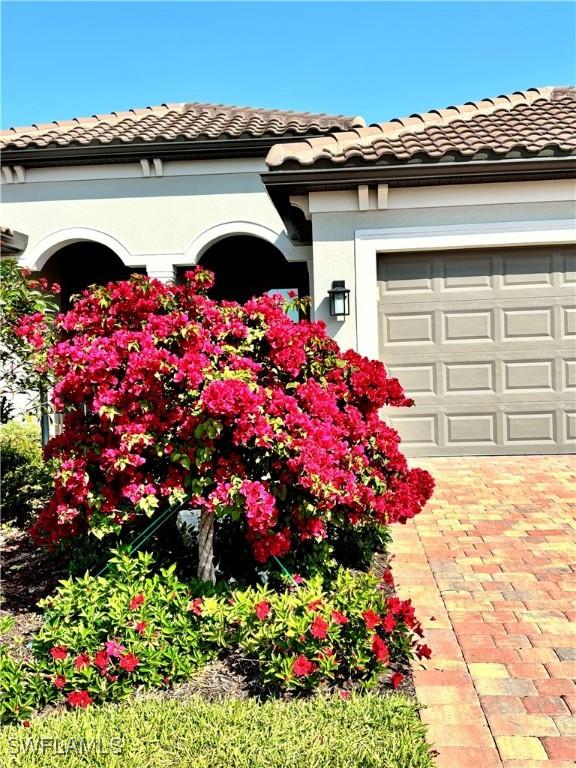 exterior space with an attached garage, a tile roof, and stucco siding