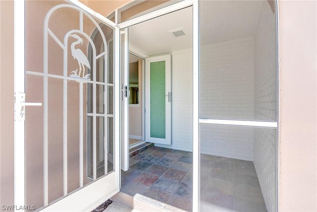 property entrance with visible vents and brick siding