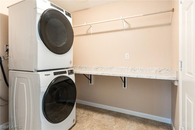 laundry area featuring light tile patterned floors and stacked washing maching and dryer