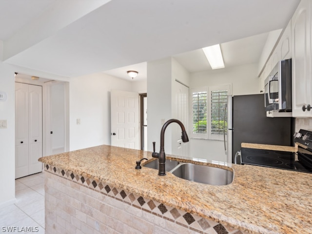 kitchen featuring stove, sink, stainless steel microwave, and white cabinets