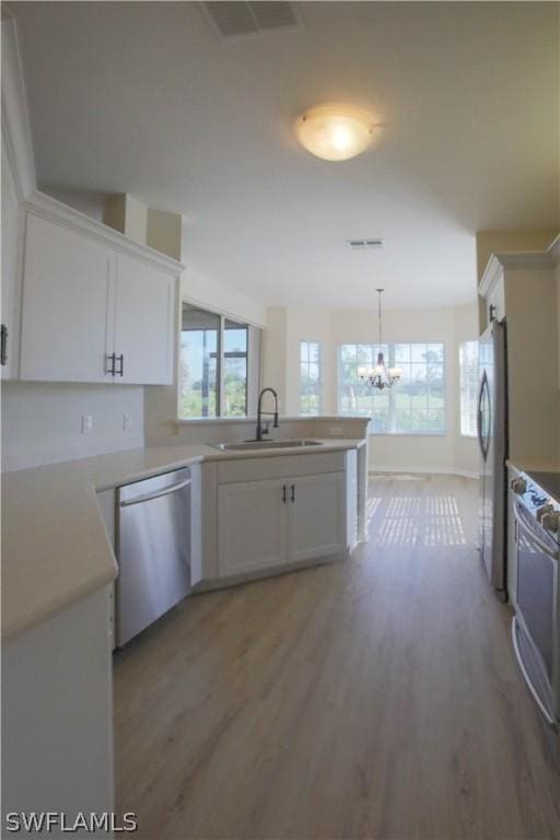 kitchen with white cabinetry, sink, decorative light fixtures, and stainless steel appliances